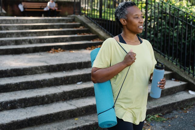 A person carrying a yoga mat and a water bottle