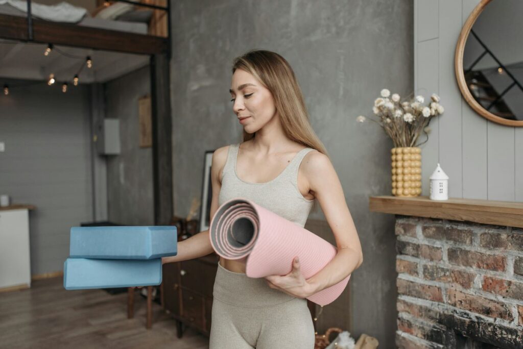 Woman holding a yoga mat and blocks at home, showing why gentle yoga is essential
when moving disrupts your routine and daily life feels unsettled.