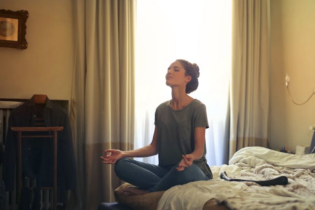 A woman meditating on her bed